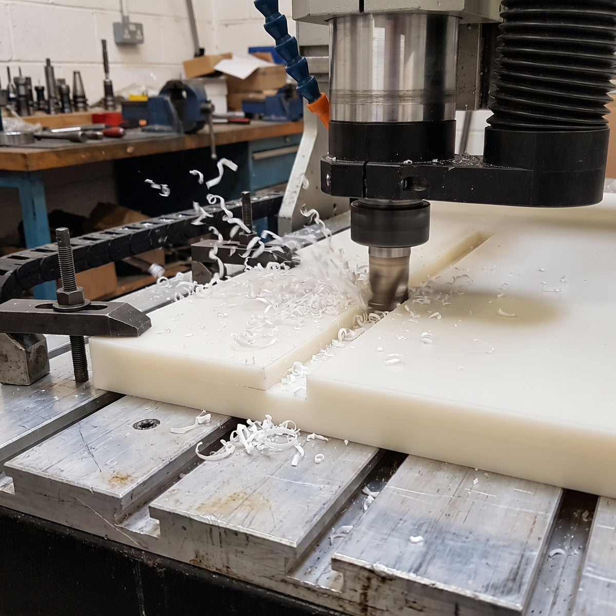 Thick natural polypropylene sheet being CNC machined with a clean slot and white plastic swarf