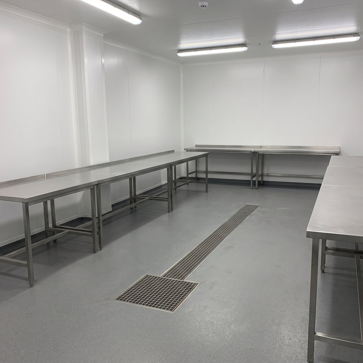 White hygienic PVC wall cladding sheets lining a food processing room with stainless steel tables